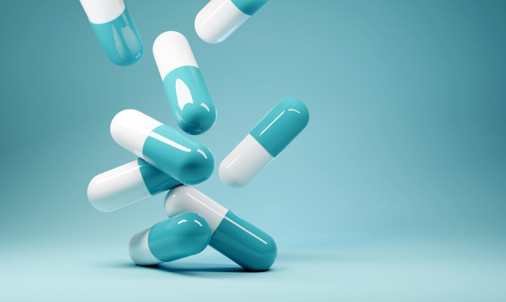 Blue and white pills falling against a light blue background