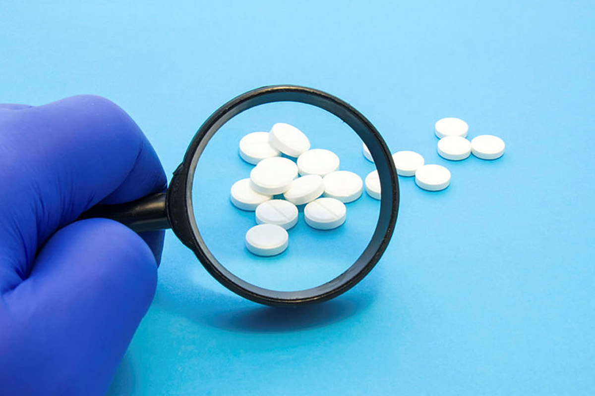 Pharmacist or expert on pharmaceutical inspection identifies pills. Testing, verification and determining pharmaceutical counterfeiting or fakes of medicines and medicinal substance quality concept.